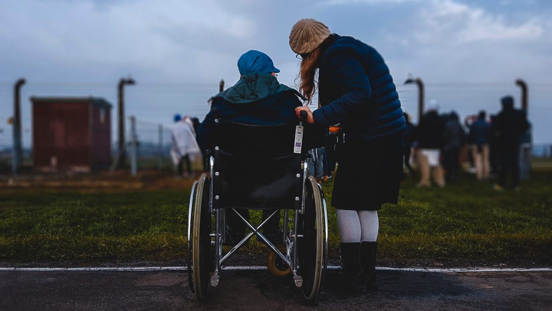 A caregiver beside a person in a wheelchair